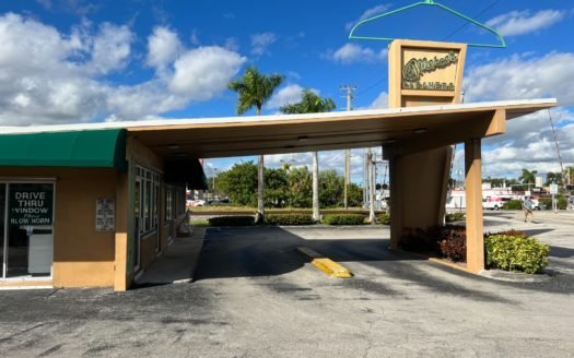 Image of an orange building with green awnings and a roof over a two lane drive through area in South Florida.